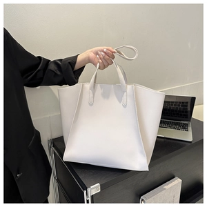 Minimalist white PU leather tote bag shown in a professional lifestyle setting with a laptop