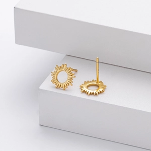 Macro detail of gold sunburst S925 sterling silver stud earrings on a white platform