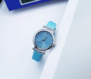 Close-up of light blue leather strap and silver watch case with sparkling rhinestones