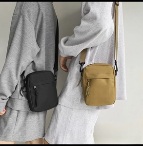 Detail of minimalist nylon crossbody bags in black and ginger yellow colors