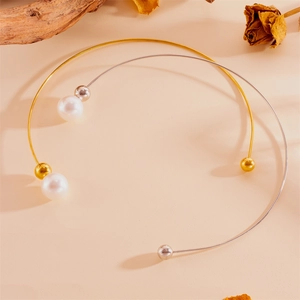 Détail de colliers choker or et argent avec de grandes perles sur un fond chaleureux