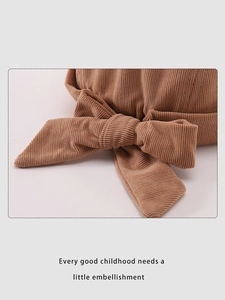 Détail du bonnet pour bébé en velours côtelé caramel avec nœud et texture