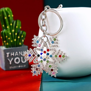 Sparkling snowflake keychain with colorful rhinestones and pearl on a white cup