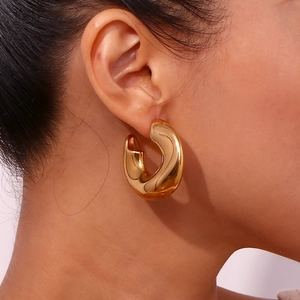 Polished 18K gold-plated irregular C-shaped chunky hoop earrings on female model