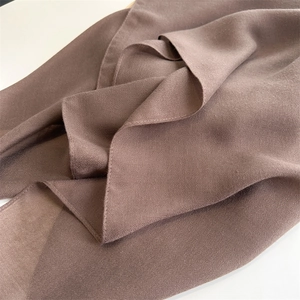 Close-up of warm brown cotton linen fabric showing smooth texture and soft drapes