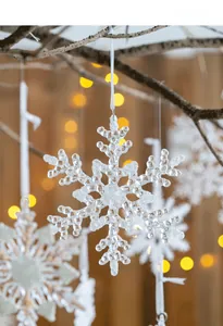 Macro shot of frosted acrylic snowflake ornament hanging with warm bokeh background