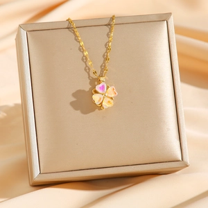 Elegant gold four-leaf clover necklace with iridescent shells on a champagne jewelry box