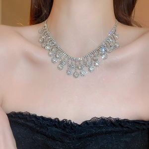 Detail shot of a sparkling crystal flower tassel necklace worn by a model on a black top