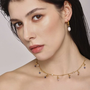 Golden freshwater pearl necklace and hoop earrings with zircon and lapis lazuli on a model