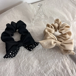 Detail of black and beige fabric scrunchies with crystal bows in a set of two