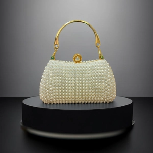 Detail of luxury pearl evening bag with gold circular handle and white faux pearls