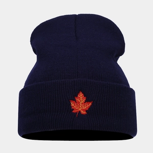 Close-up of red maple leaf embroidery on a dark blue knitted beanie with folded cuff