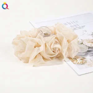 Close-up of a cream chiffon rose hair claw clip with satin petals and transparent teeth