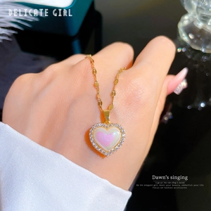 Close-up of heart-shaped opal pendant with micro-set zircons on a gold chain