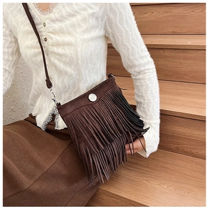 Close-up of a brown tassel crossbody bag with metallic ring and soft suede texture