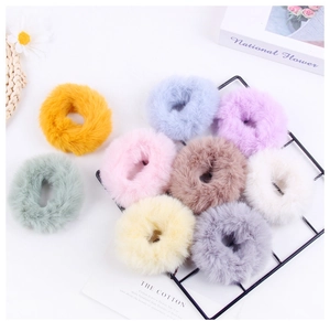 Multiple colorful plush scrunchies in pastel tones arranged on a white background