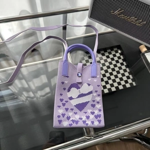 Détail du mini sac en tricot violet avec motifs de cœur et texture tissée épaisse