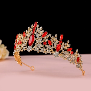 Detail showing golden baroque crown with red marquise gemstones and small white rhinestones
