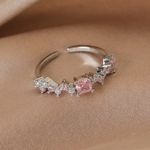 Macro shot of pink heart-shaped zircon ring with adjustable open band on satin silk