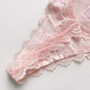 Close-up of pink lace texture and mesh fabric detailing on sweet style thong