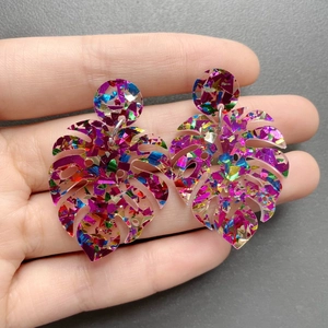 Macro shot of colorful glitter acrylic monstera leaf earrings with round stud connector