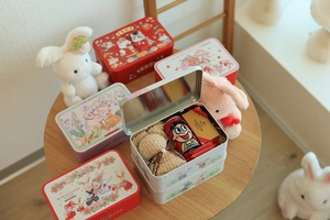 Detailed close-up of rabbit-themed tin gift boxes with festive snacks and plush bear decor