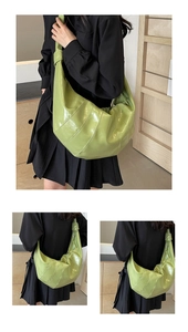 Detail of green patent leather crossbody bag with decorative diagonal stitching design