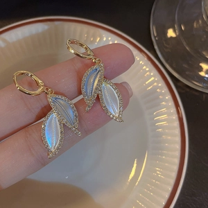 Macro shot of gold-rimmed leaf earrings with iridescent shell inlay and crystal accents