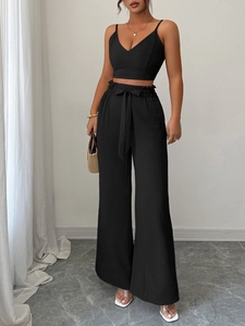 Dettaglio del crop top nero con scollo a V e pantaloni larghi a vita alta con fiocco