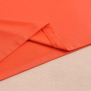 Detail of flatlock stitching and hem finish on an orange knitted backless maxi dress