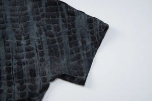 Detail of sleeve cuff showing textured crocodile pattern on dark grey mini dress