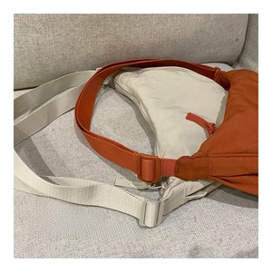 Detail of nylon crescent bags in orange and beige with adjustable shoulder straps