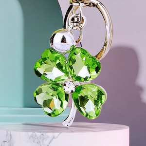 Macro view of green crystal four-leaf clover keychain with silver metal ring and faceted detail