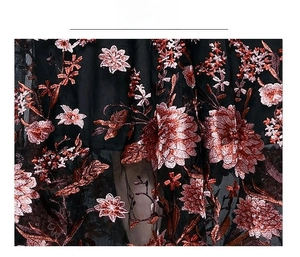 Macro shot of heavy embroidery floral patterns on black mesh dress fabric
