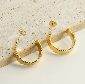 Vue détaillée des boucles d'oreilles créoles C en acier plaqué or 18K avec finition texturée