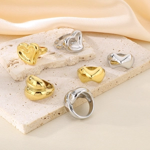 Golden and silver stainless steel heart and knot rings set on beige stone and silk