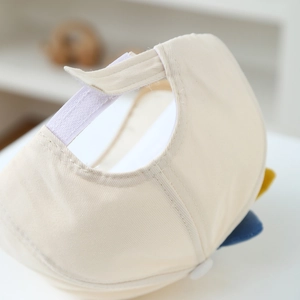 Detail of adjustable hook-and-loop strap on beige cotton baseball cap for kids