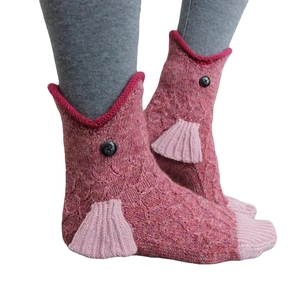 Creative pink knit crocodile socks with 3D fins and fish scale texture on white background
