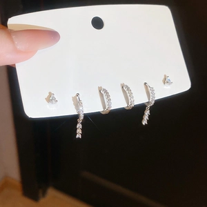 Detail of silver tassel earrings and zircon stud set held on a white display card