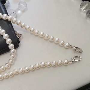 Detail of white faux pearl chain with silver lobster clasps on a white background