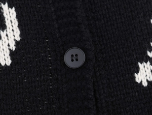 Close-up of black knit cardigan with white jacquard pattern and classic round button