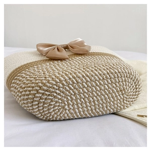 Detail of hand-woven straw tote featuring a large champagne satin bow decoration