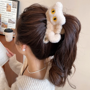 Détail d'une adorable pince à cheveux en peluche crème en forme de chat sur une coiffure