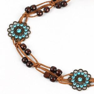 Macro detail of hand-woven brown cord belt with bronze flowers and turquoise stones