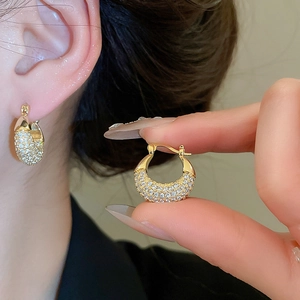 Close-up of gold pavé zircon hoop earrings showing detailed sparkling craftsmanship