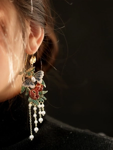 Gros plan de boucles d'oreilles papillon vintage avec grenade en émail et perles