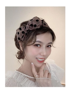 Close-up of a brown polka dot fabric bow headband worn elegantly by a model