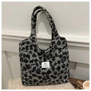 Detail of grey leopard print plush tote bag with fabric label on knit blanket background