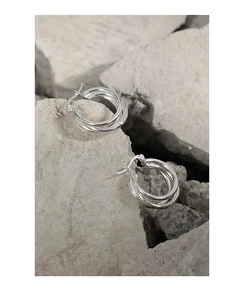 Macro shot of polished S925 silver triple-layered hoop earrings on gray stone background