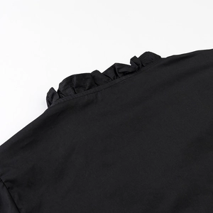 Detailed close-up of the black shirt ruffled collar and delicate fabric texture